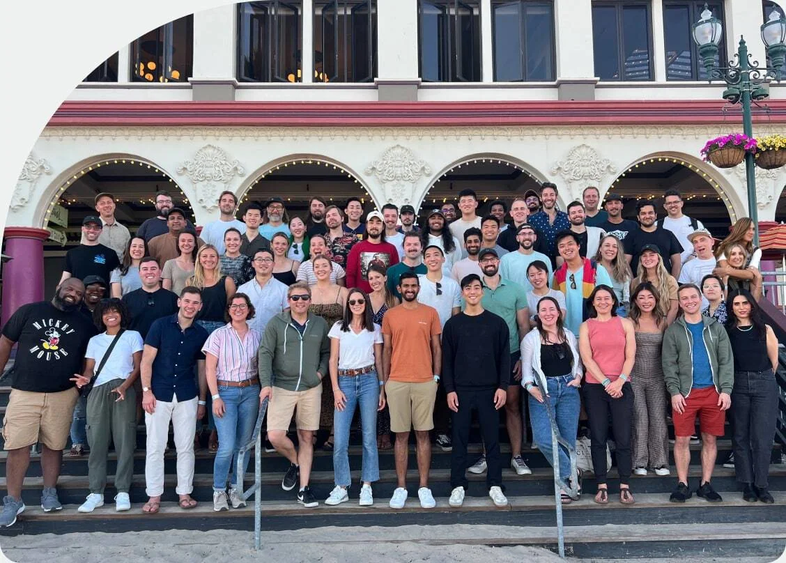 The whole Found team, around a hundred people, posed together on the steps of an arched seafront building