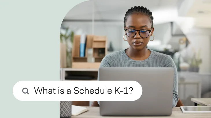 A woman working at a laptop in an office, with a search bar overlay reading 'What is a Schedule K-1?'