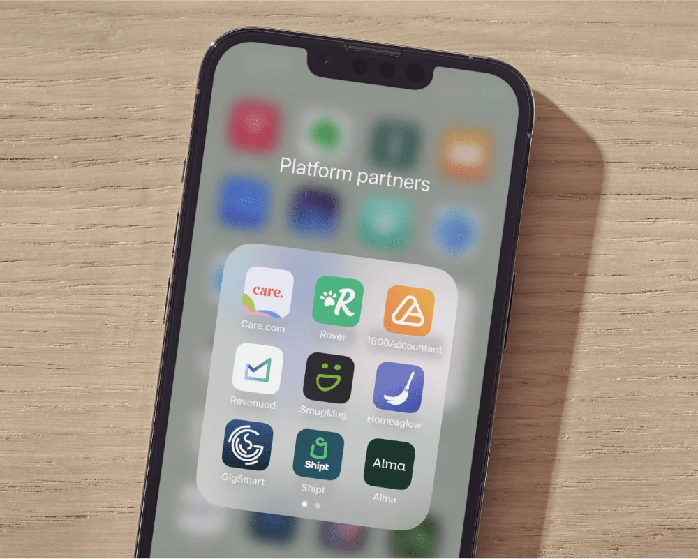 A phone on a desk showing a folder of partner apps—Care.com, Rover, 1800Accountant, Revenued and SmugMug—labelled Platform partners