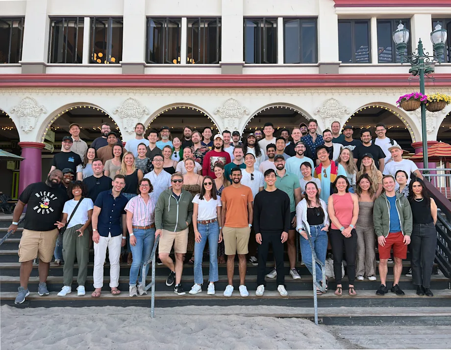 The whole Found team posed together on the steps of an arched seafront building